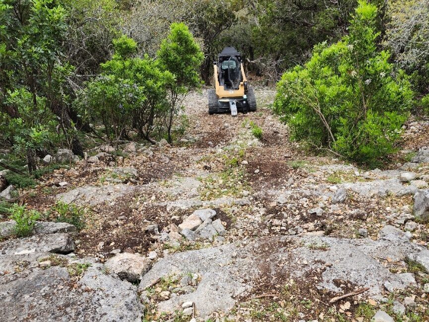 Rocky ground before milling, with a skid steer in the background