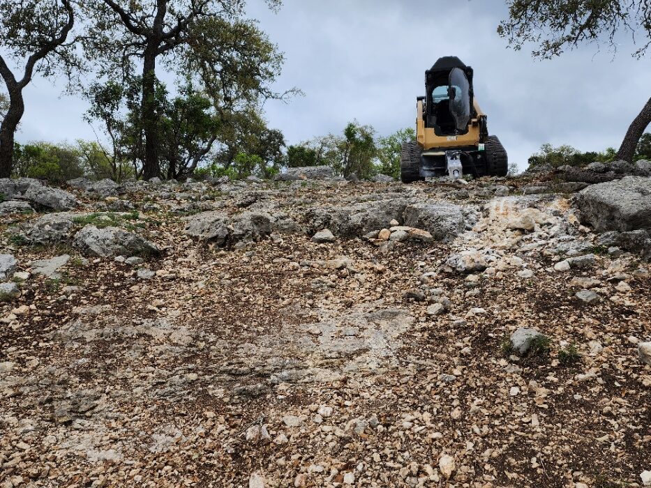 Rock slope before milling, with a skid steer at the top