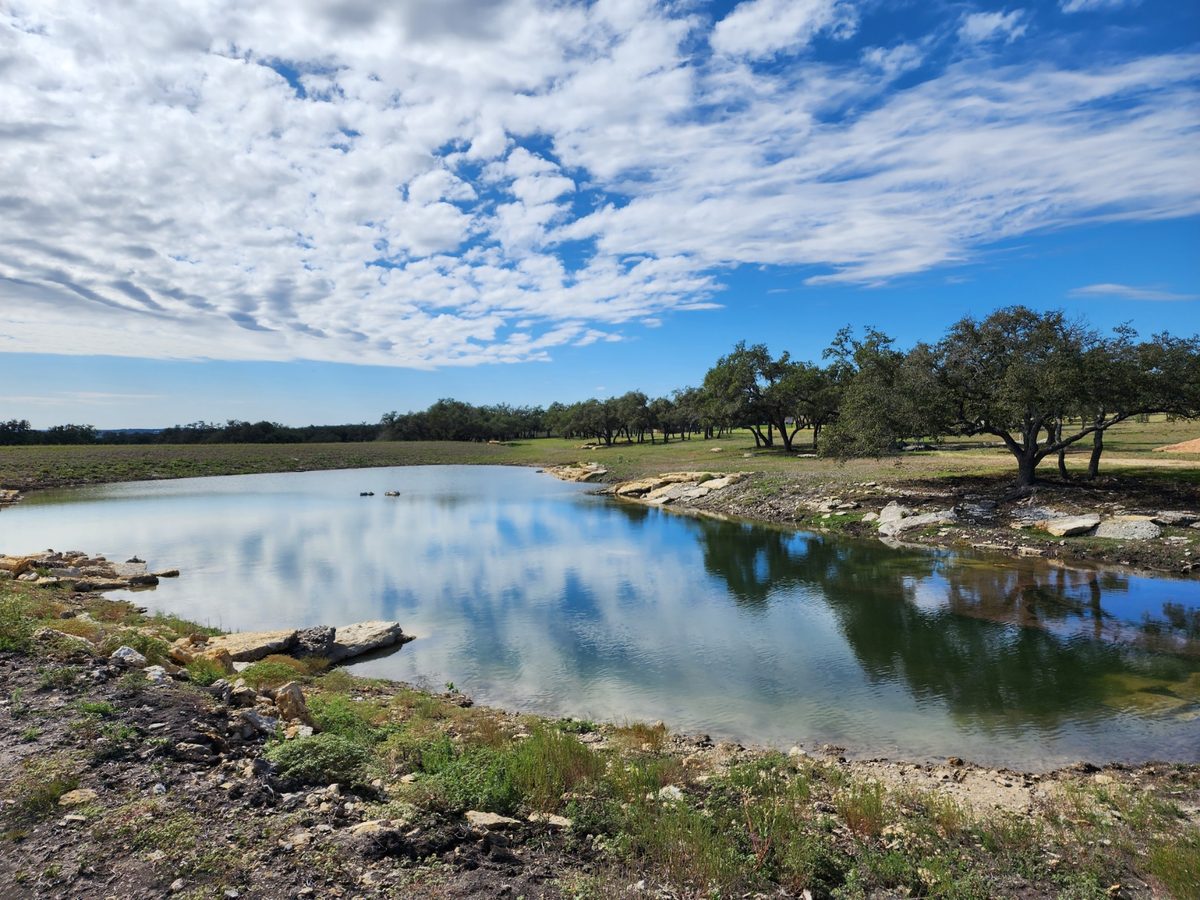 Pond with clouds reflected in the water and rock along the near shore