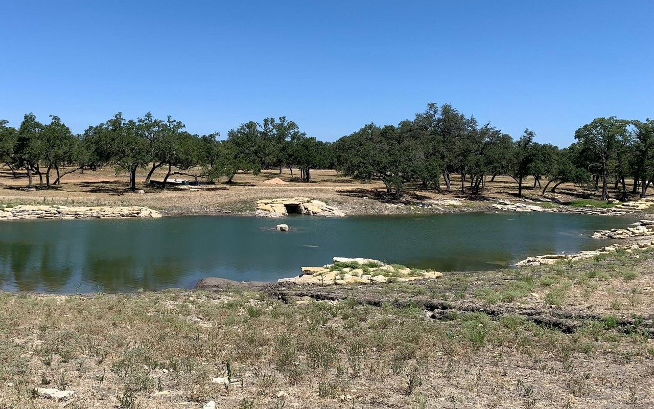 The same stone-lined pond later, with clear green water and settled banks