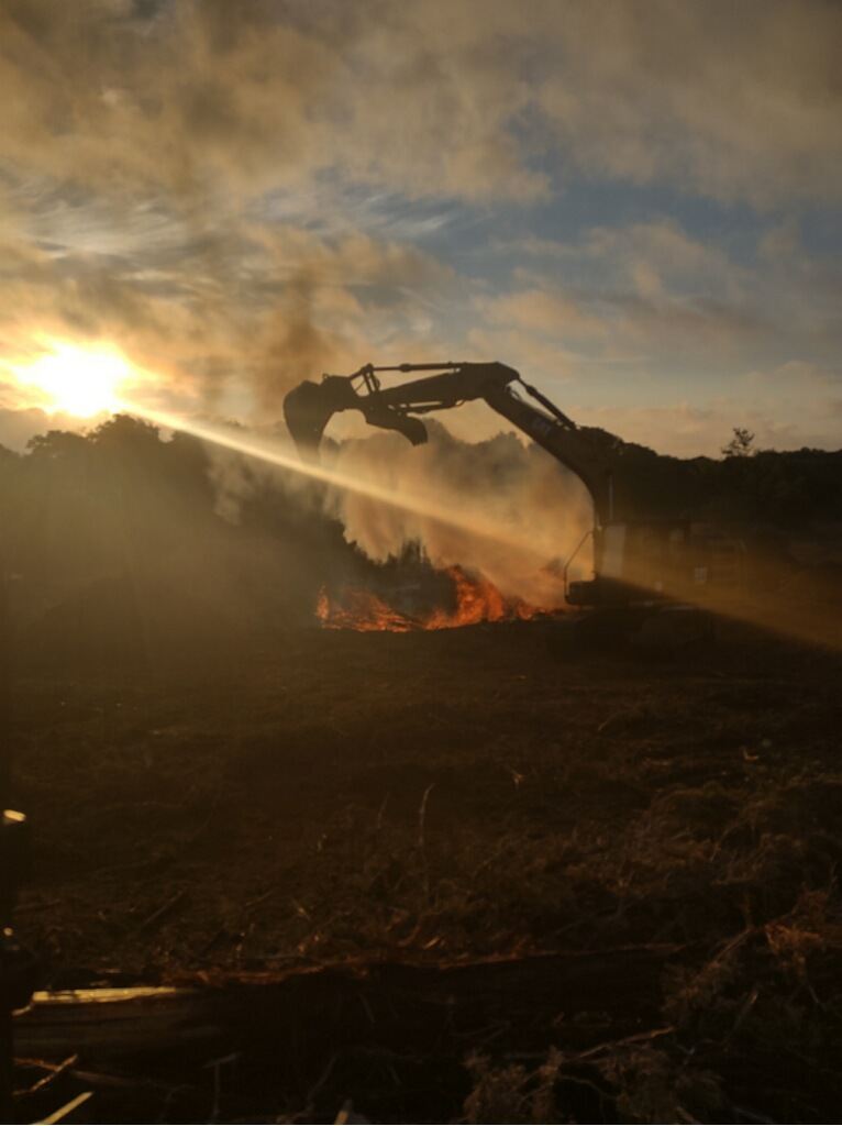Controlled burn-down of cleared brush at sunset