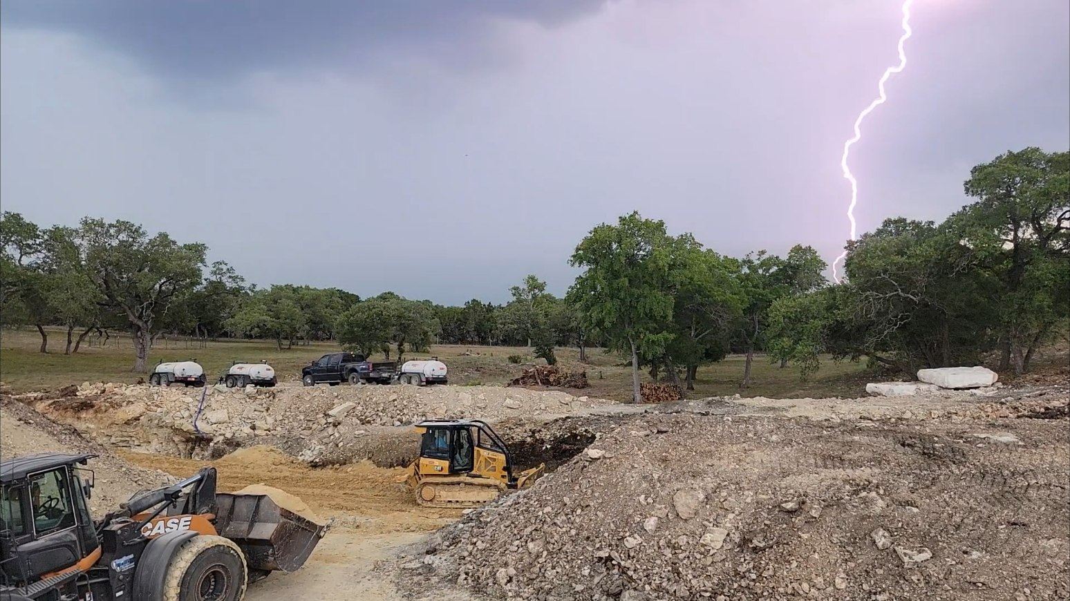 Road and pond work under a Hill Country storm